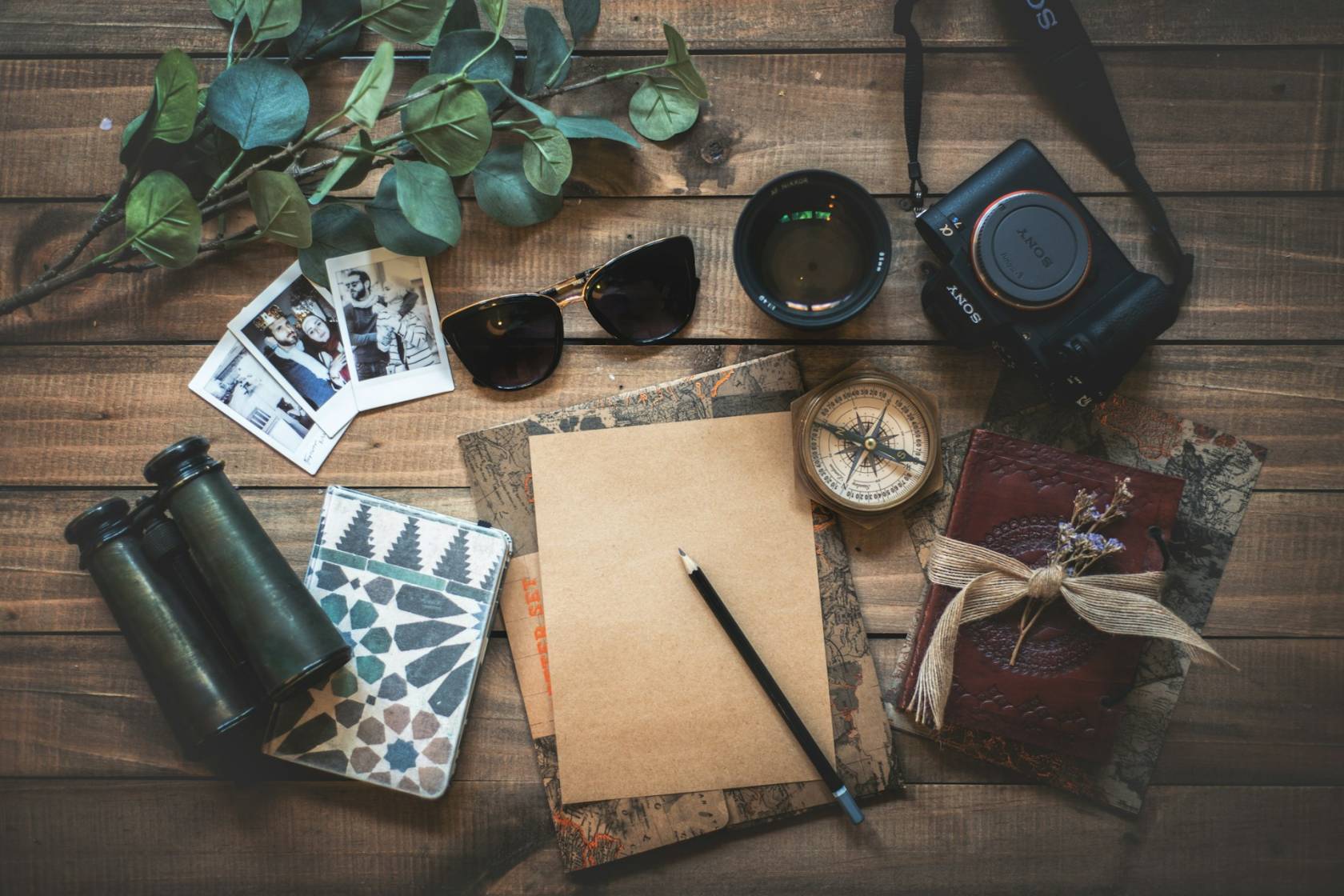 "Flatlay of a journal, camera, map, sunglasses, and passport on a wooden table with a cup of coffee, representing travel diary creation on Instagram."